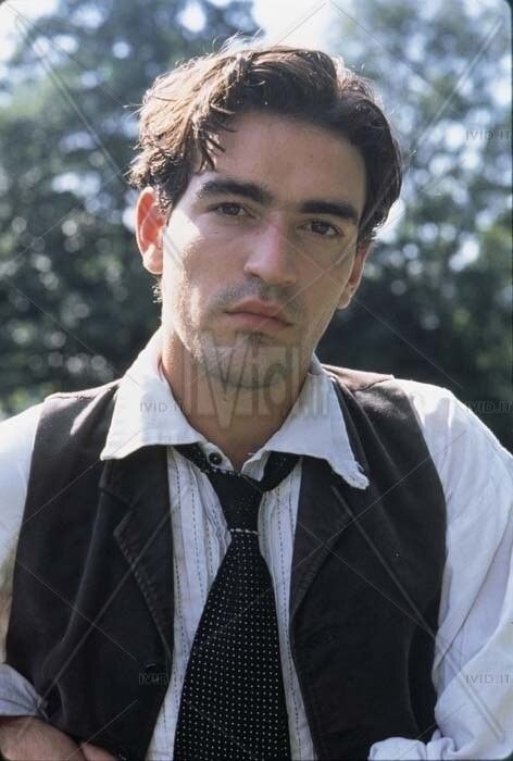 a young man wearing a vest and tie