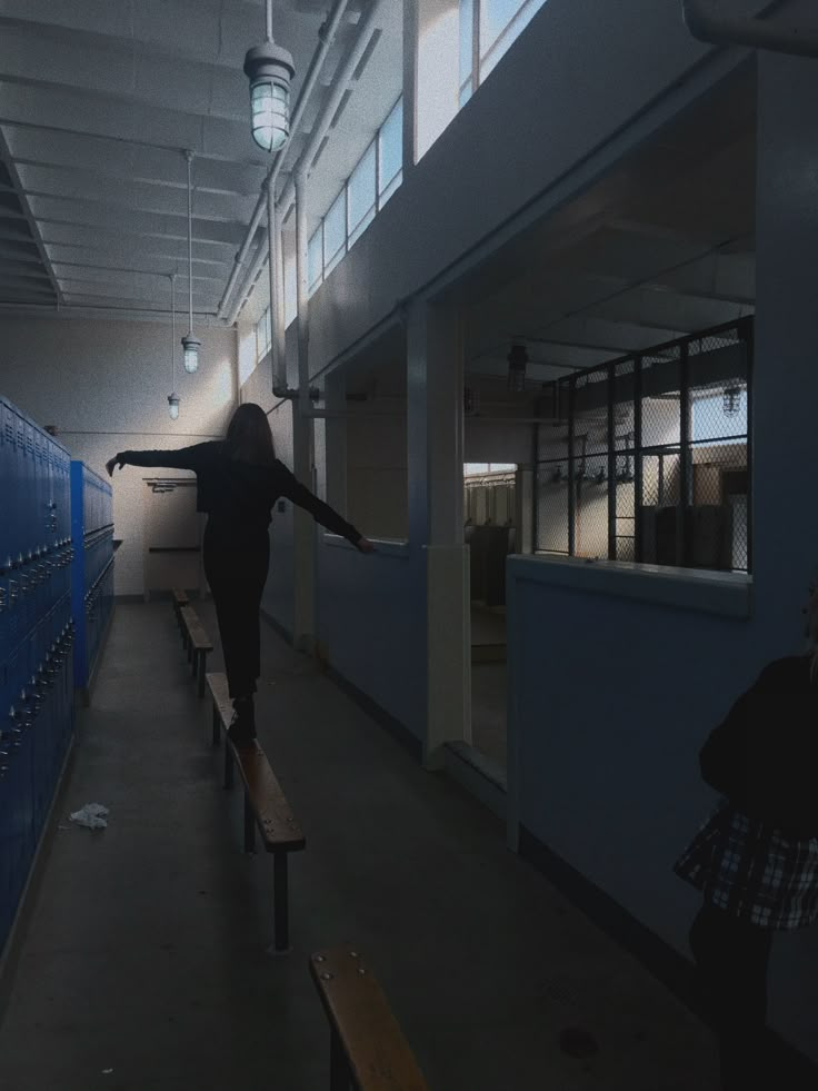 a person standing on top of a bench in a room with blue lockers behind them