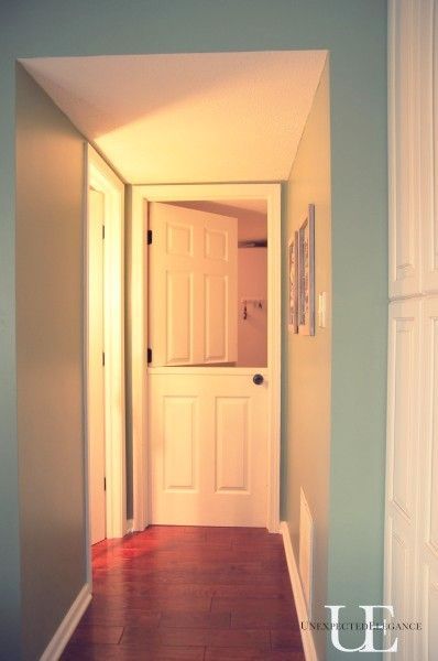 an empty hallway with white doors and hard wood flooring on either side of the door