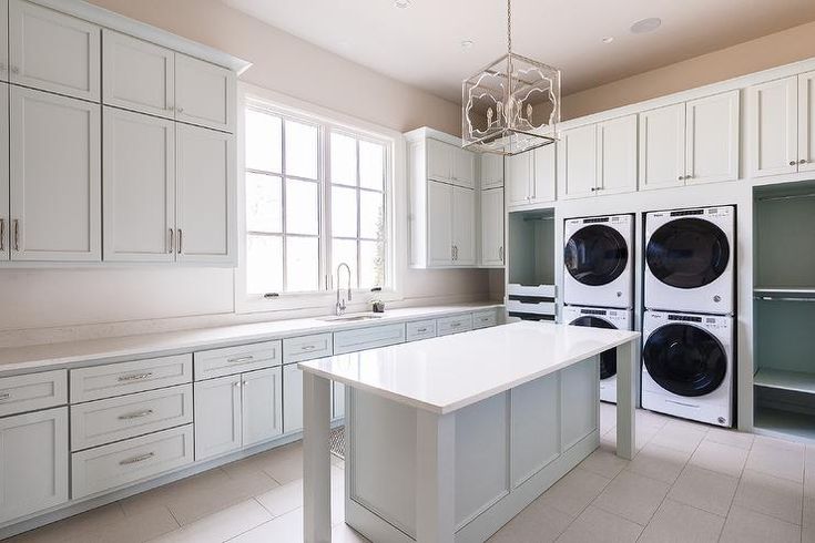 a kitchen with white cabinets and an island in front of the washer and dryer