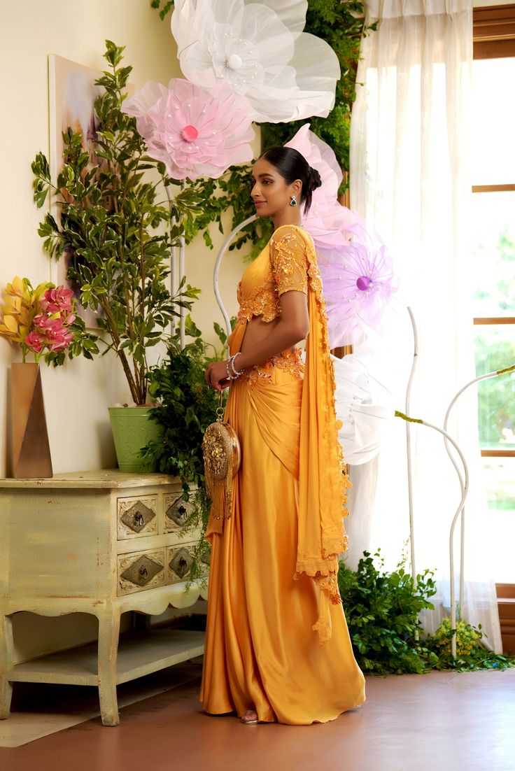 Letting it flow for this season is the way to go. This flowy pre-draped saree is made for everyone who wants to be comfortable at their soirees. The trail of the saree is embellished with flowers so that you can leave your sparkle everywhere you go. Blouse with embroidered sleeves and the sleek shine of the satin fabric on the chest. hook at the back of the blouse. A pre-draped saree with a comfortable fit comes with an embroidered waistline. a concealed zip at the back of the saree From Moledro Floor-length Pre-draped Saree With Gota Work For Wedding, Evening Anarkali Pre-draped Saree For Eid, Anarkali Style Pre-draped Saree For Eid Evening, Evening Anarkali Pre-draped Saree With Cutdana, Bollywood Style Draped Tissue Silk Dupatta, Pre-draped Saree With Gota Work For Navratri Reception, Anarkali Pre-draped Saree For Evening With Cutdana, Draped Saree For Reception And Navratri, Draped Saree For Reception During Navratri