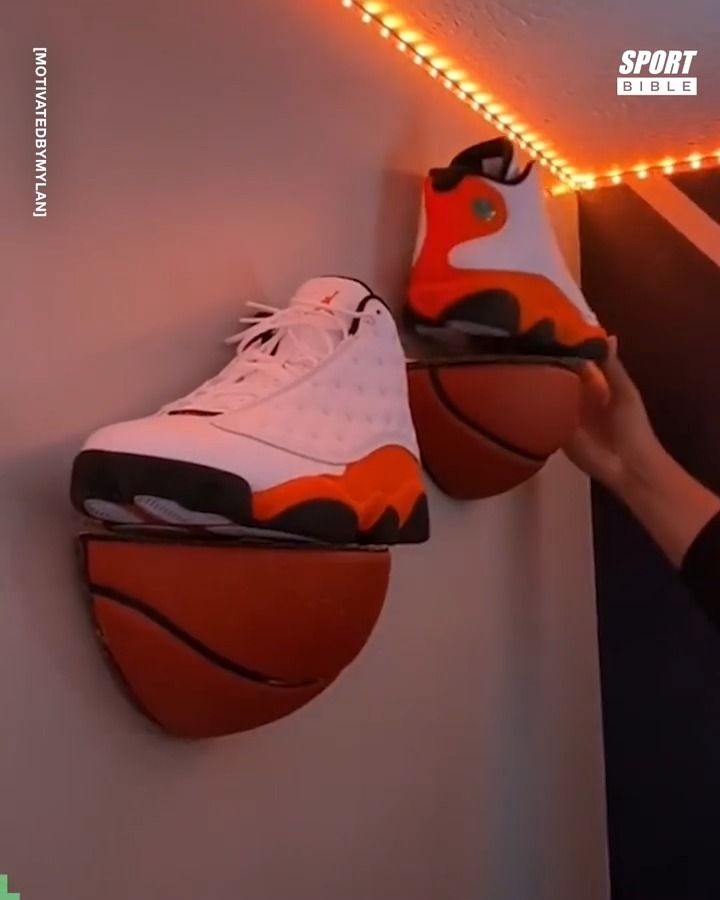 a person is holding a basketball on top of a shoe that's mounted to a wall