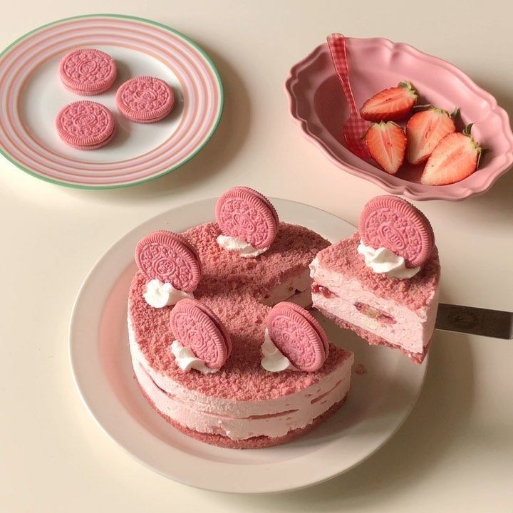 there is a cake with pink frosting on it and some strawberries next to it