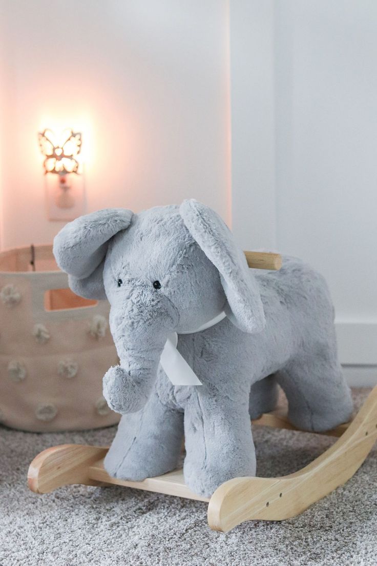 a stuffed elephant sitting on top of a wooden rocking toy