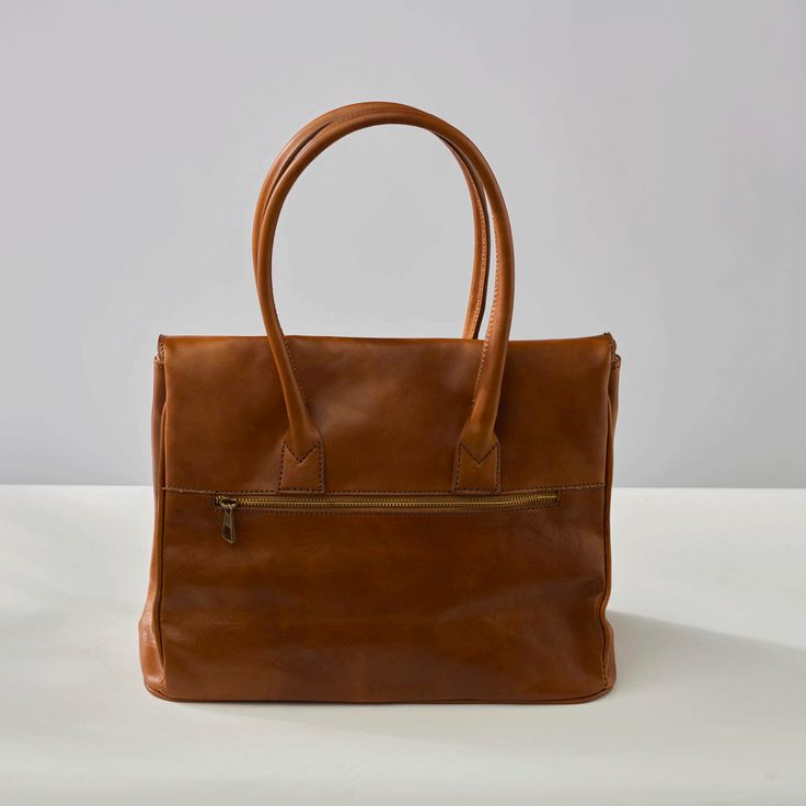 The Antonella Tote Bag is a office-appropriate carryall and that 'something sleek' for your 9-to-5 routine. The stunning cognac leather will develop an authentic patina over time, making it even more luxurious looking. Comes with Hektor + Helena's Lifetime warranty and guarantee. Made of Italian vegetable tanned leather, our bags are all handmade by master craftsmen who have been perfecting their skills for generations. The result is a striking blend of rich earth-toned colors, providing a glowi Cognac Briefcase With Leather Handles For Office, Cognac Leather Briefcase For Office, Leather-lined Satchel Bag For Work, Timeless Cognac Satchel With Leather Handles, Leather Lined Satchel Bag For Work, Leather Lined Tote Briefcase For Work, Leather Lined Double Handle Briefcase For Work, Double Handle Leather Lined Briefcase For Work, Cognac Briefcase With Leather Handles