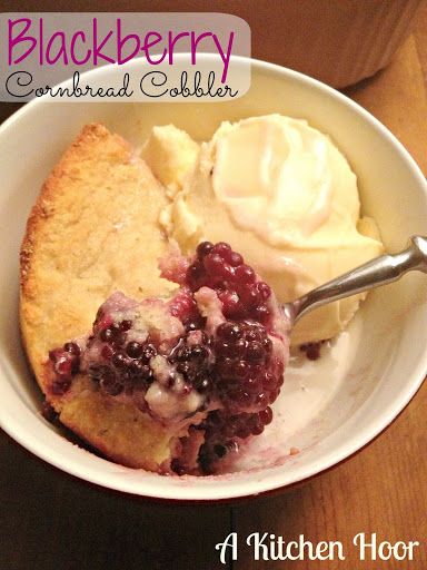 a white bowl filled with ice cream and berry cobbler on top of a wooden table