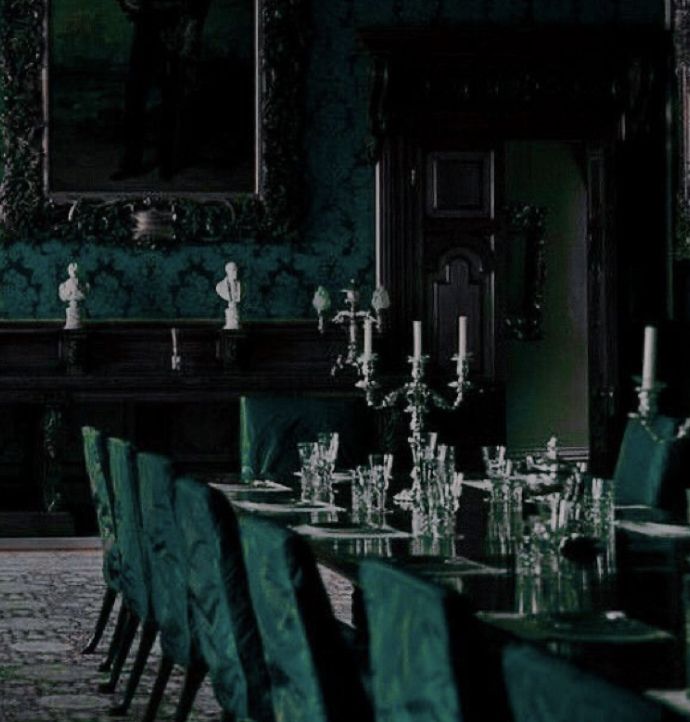 an empty dining room with green chairs and walls covered in ornate wallpaper, along with chandeliers