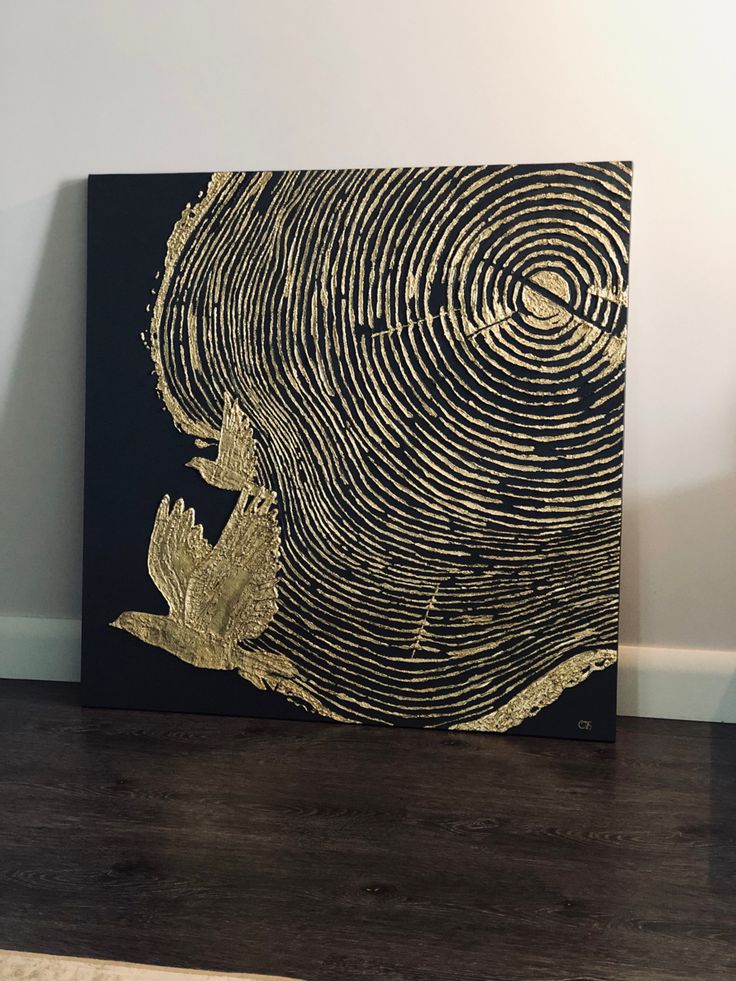 a black and gold painting on a wooden floor