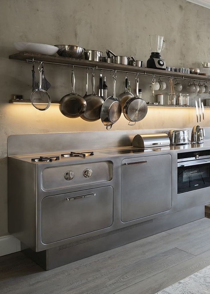 an industrial style kitchen with stainless steel appliances and cooking utensils on the wall