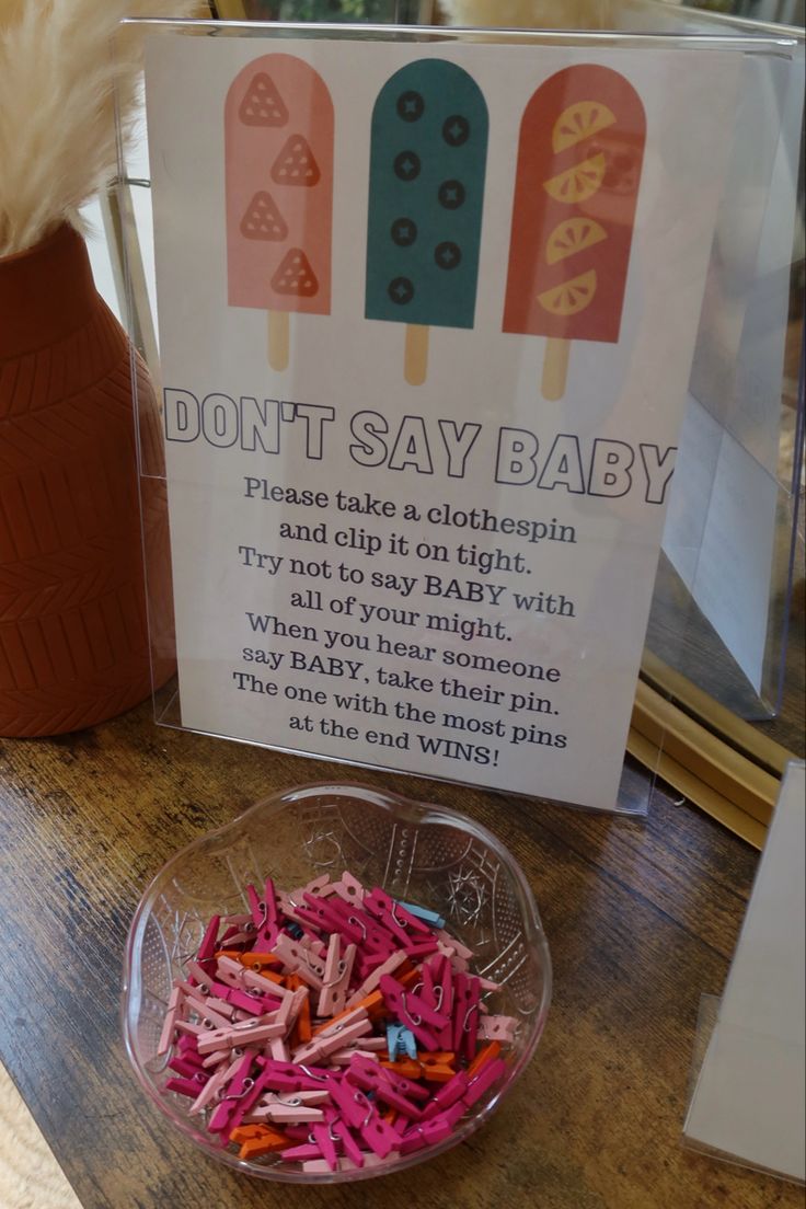 a bowl filled with candy sticks next to a sign that says don't say baby