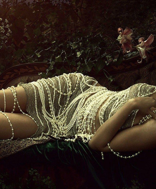 a woman is laying on the ground with beads all over her body and hands behind her head