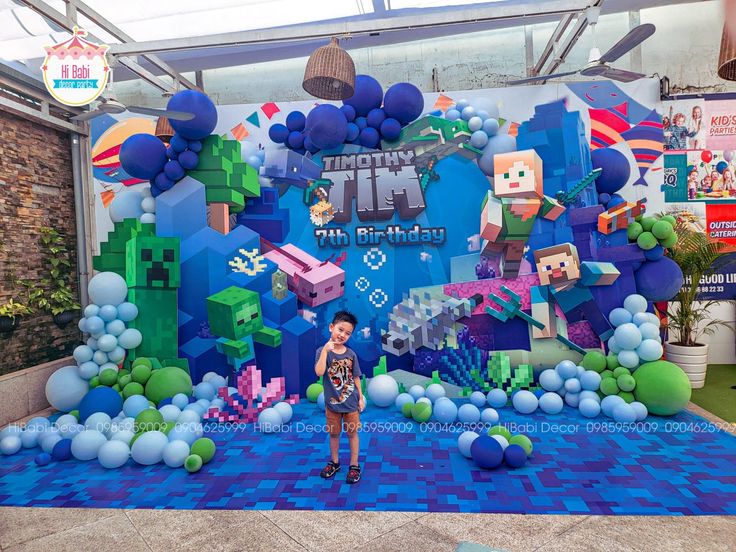 a person standing in front of a blue and green backdrop with legos on it