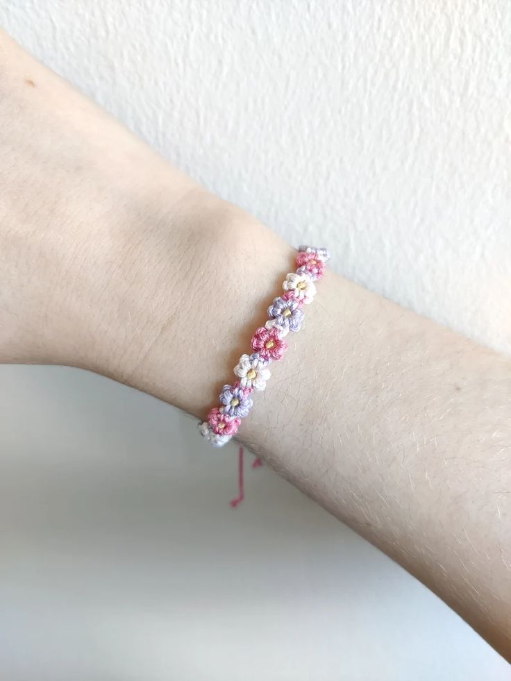 a woman's arm with a pink and white beaded bracelet on top of it