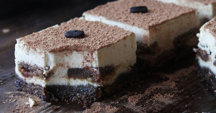 three pieces of cake sitting on top of a wooden cutting board with chocolate chips and oreo cookies