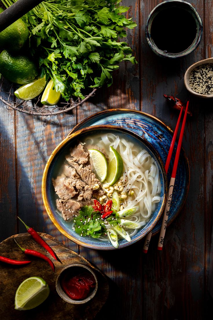 an overhead view of a bowl of pho noodle soup with chopsticks