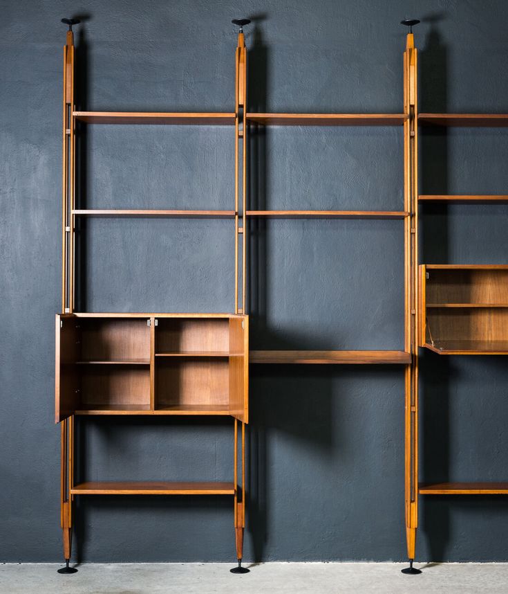 two wooden bookshelves against a gray wall