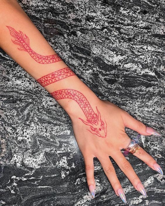 a woman's arm with a tattoo on it and a red dragon on the wrist