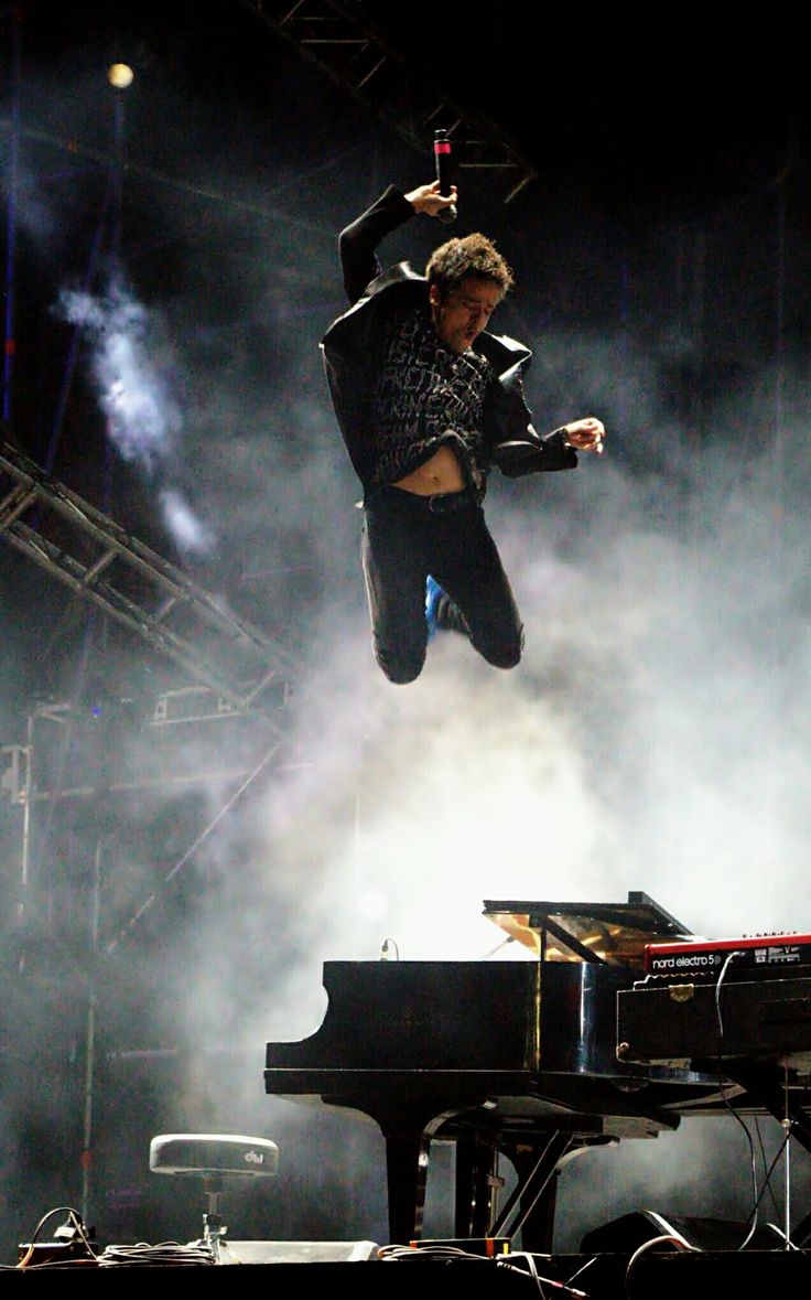 a man is jumping in the air over a piano and keyboard at a music festival