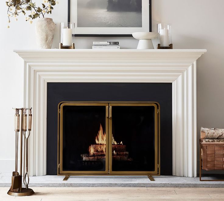 a fire place in a living room with a painting on the wall and candles around it