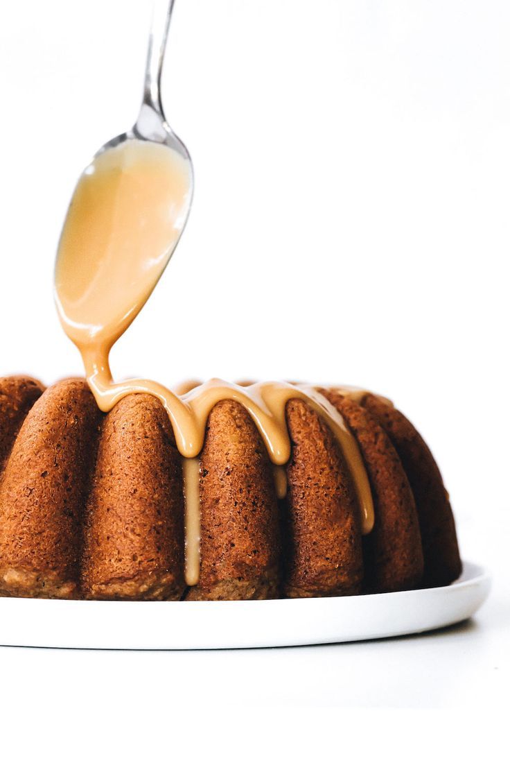 a white plate topped with a bundt cake covered in caramel sauce and drizzled with icing