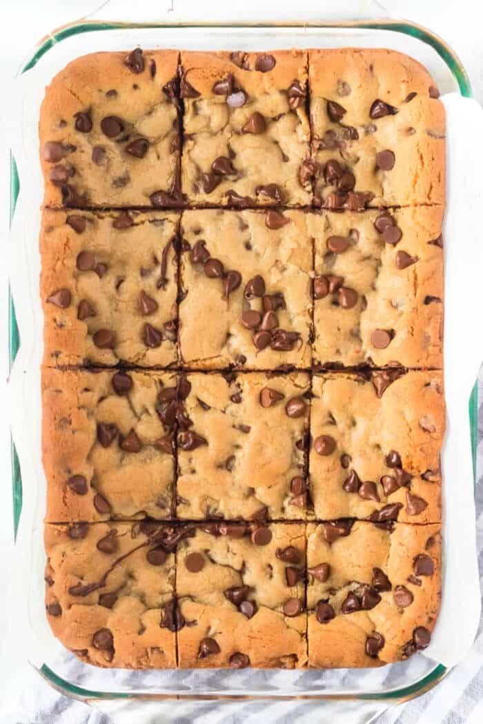 chocolate chip cookie bars cut into squares in a glass baking dish on a white towel