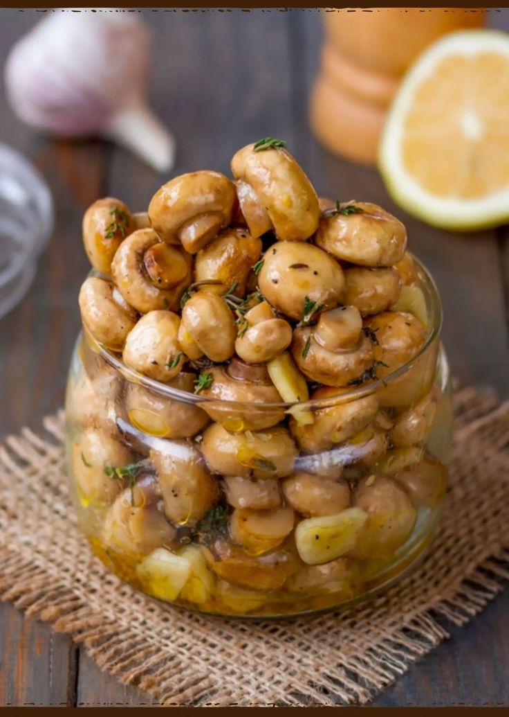 a glass jar filled with cashews on top of a wooden table next to an orange slice