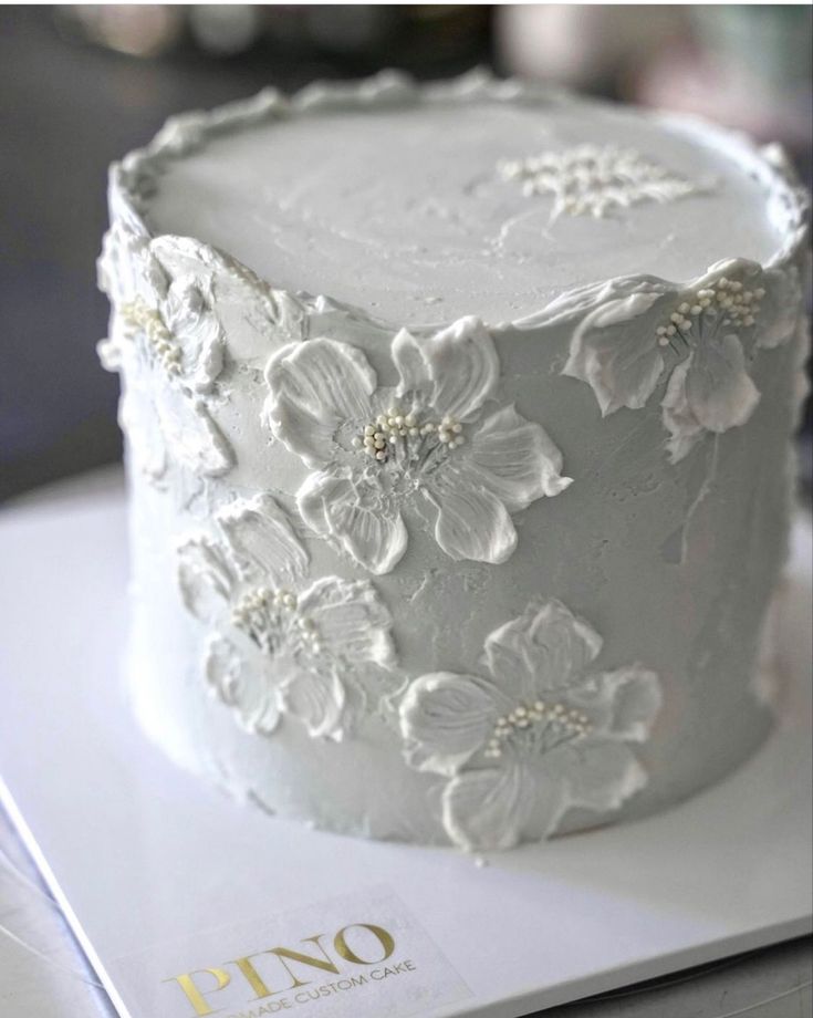 a white cake with flowers on it sitting on top of a table next to a magazine