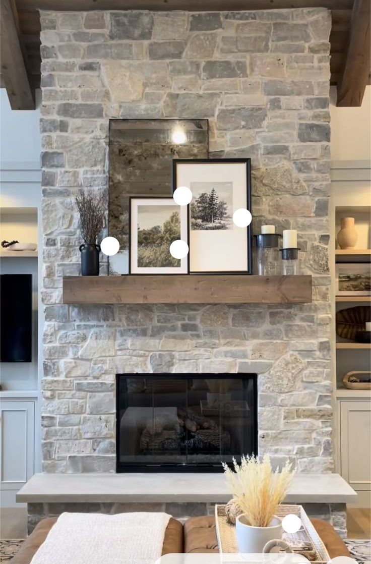 a living room with a stone fireplace and pictures on the mantle above it, along with other furniture