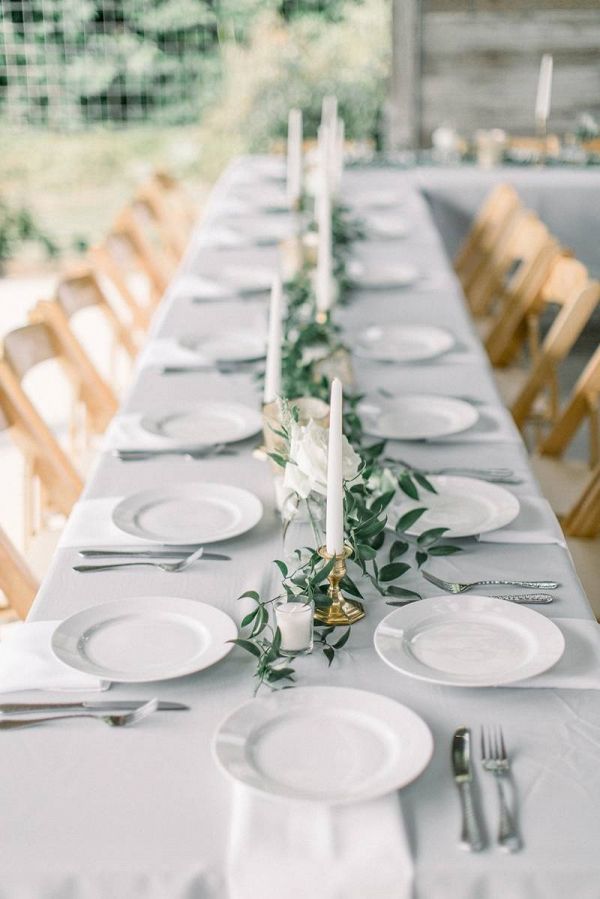 a long table with white plates and silverware is set up for an elegant dinner