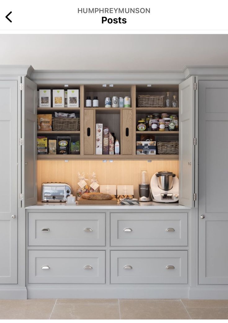 an organized kitchen with gray cabinets and white counter tops, along with coffee maker on the far wall