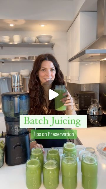 a woman standing in front of jars filled with green smoothies and drinking from a blender