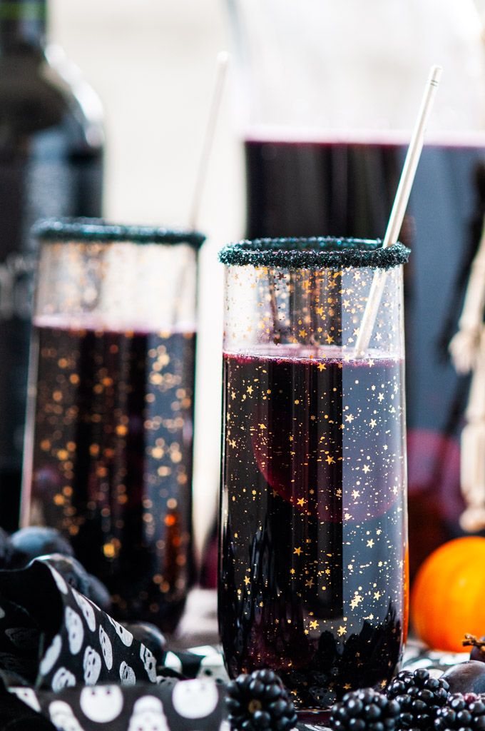 two glasses filled with liquid sitting on top of a table next to oranges and blackberries