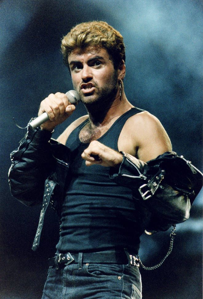 a man holding a microphone in his right hand and wearing gloves on the other side