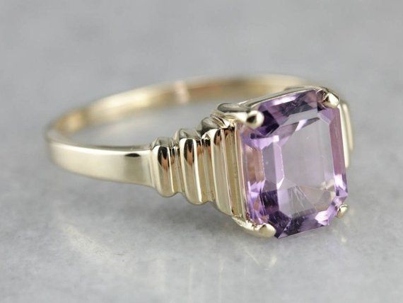 Outstanding! This modern yellow gold setting perfectly frames the amethyst we've set at the center! The tapering stepped yellow gold band looks soft and elegant on the finger, while the rich purple gem glitters with violet sparkles! Metal: 14K Yellow Gold Gem: Amethyst 2.85 Carats Gem Measurements: 7.8 x 9.9 mm, Emerald Cut Ring Size: 10 Marks: "14K UP" Stamped on the inside band Modern Yellow Gold Amethyst Ring For Wedding, Modern Yellow Gold Amethyst Wedding Ring, Gold Solitaire Amethyst Ring For Formal Occasions, 10 Marks, Purple Gems, Emerald Cut Rings, Rich Purple, Vibrant Purple, Yellow Gold Setting