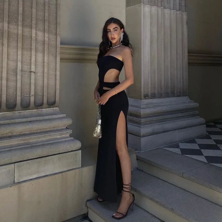 a woman in a black dress standing on some steps