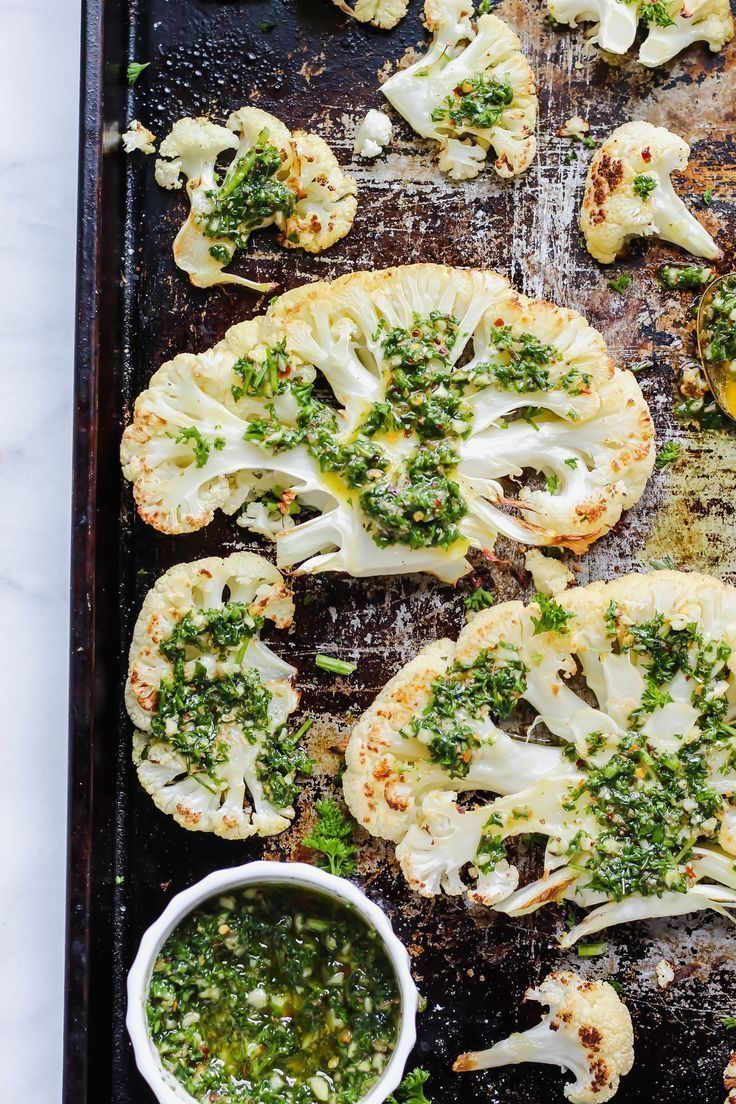 broccoli and cauliflower on a baking sheet with pesto sauce in a bowl