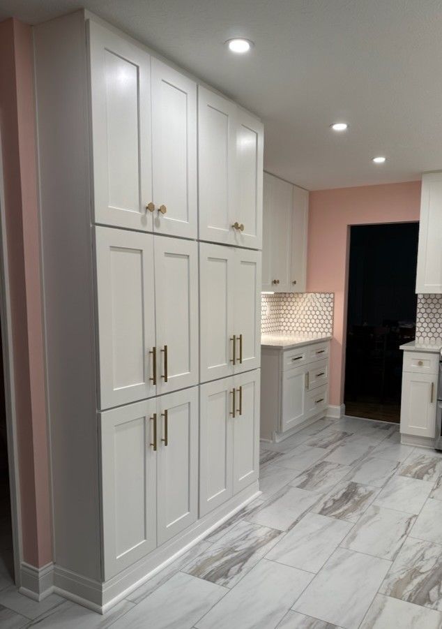 an empty kitchen with white cabinets and marble flooring is pictured in this image from the front view