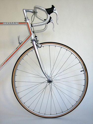 a silver bicycle with a black and white bike on the front wheel is leaning up against a wall