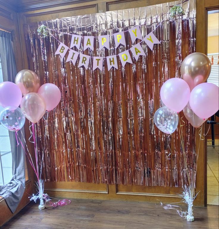 balloons and streamers in front of a happy birthday banner on a door frame with ribbons