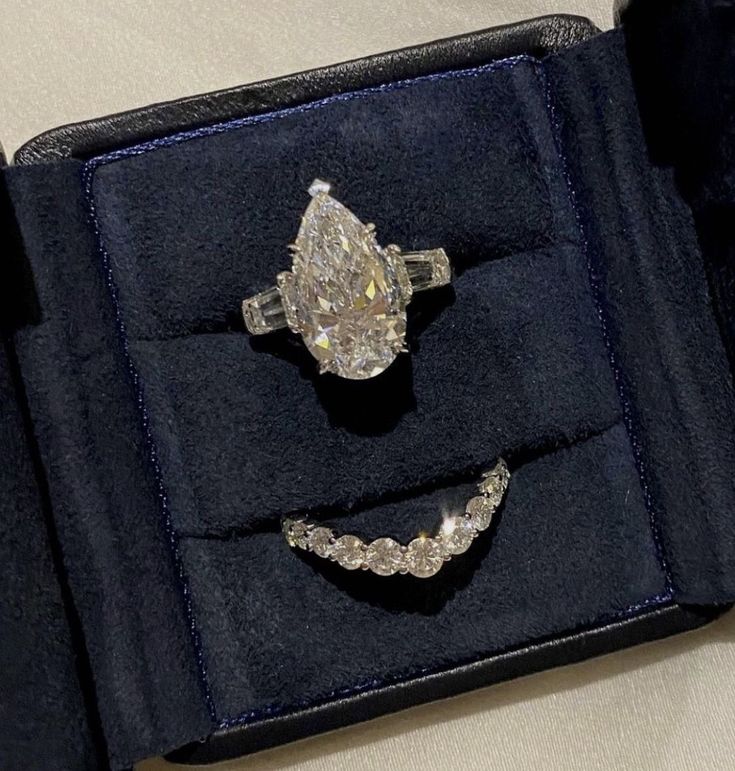 an open ring box with two engagement rings in it and one diamond set on top