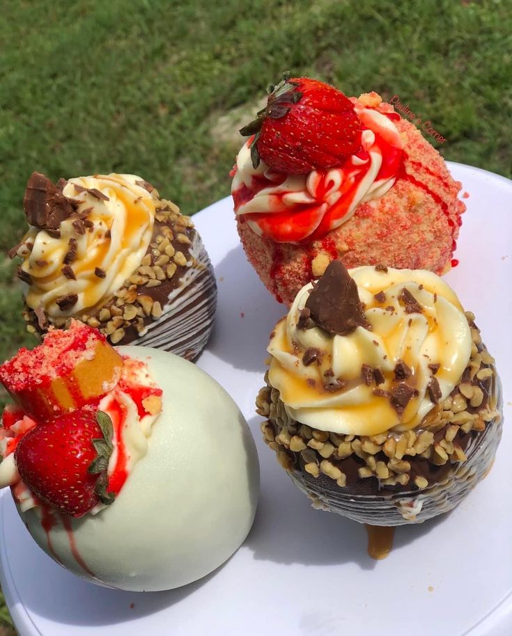 four cupcakes on a white plate with strawberries