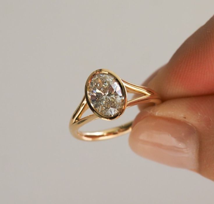 a woman's hand holding a yellow gold ring with a white diamond in it