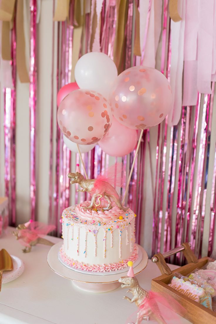 a birthday cake with pink and white balloons