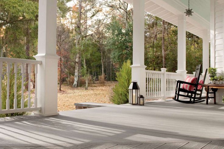 a porch with rocking chairs on it and trees in the backgroung area