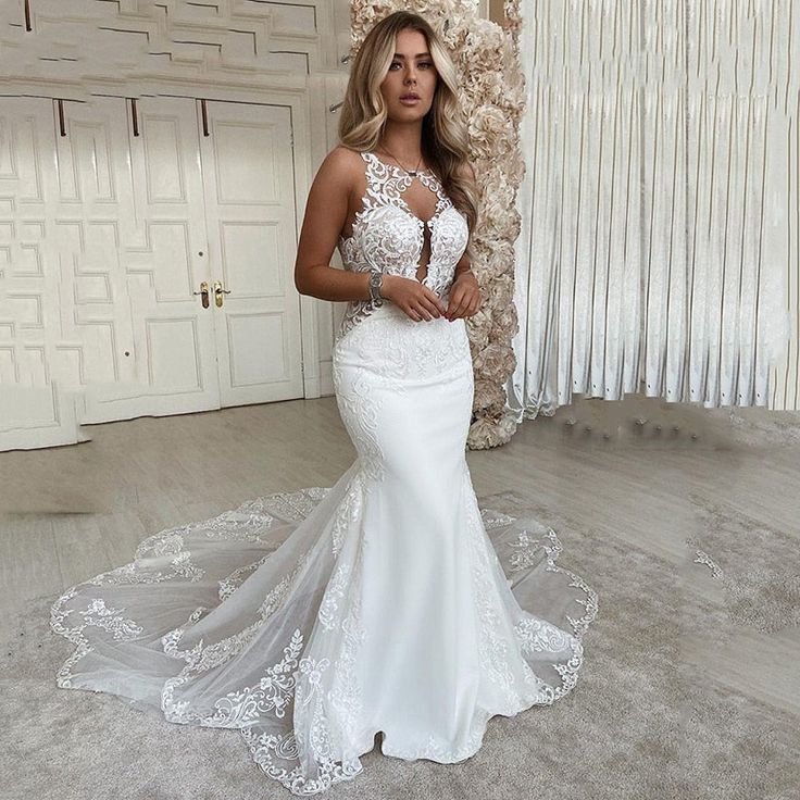 a woman in a white wedding dress standing next to a wall and posing for the camera