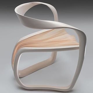 an unusual chair made out of plywood and white paint on the back, sitting in front of a gray background