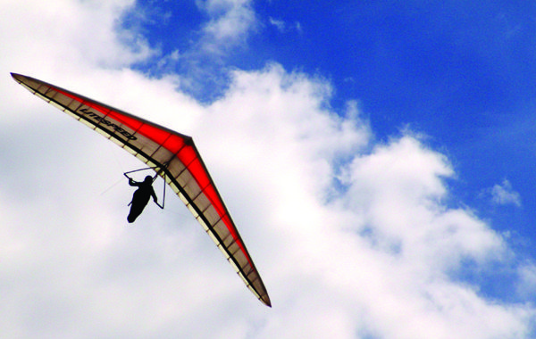 a person is flying a large kite in the blue sky with white clouds behind them