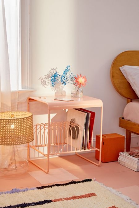 a room with a bed, table and lamp on the floor in front of a window