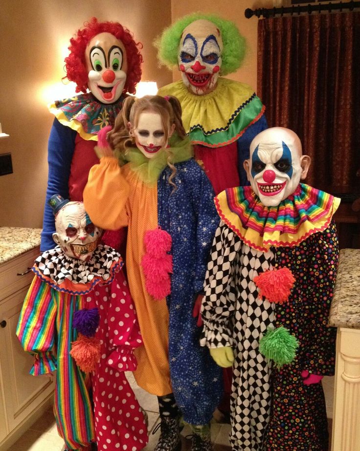 a group of clowns standing next to each other in a kitchen with lights on