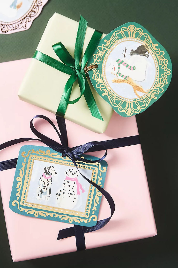 two gift boxes wrapped in pink and green paper with black ribbon, decorated with images of dogs on them